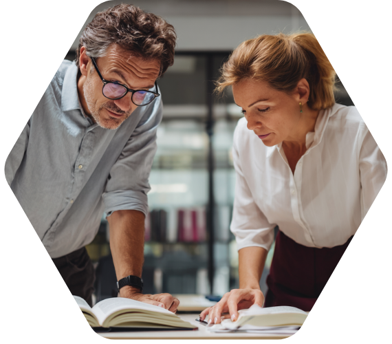 Zwei Schulleitungen beugen sich über Fachliteratur – Austausch über rechtliche Grundlagen im Schulalltag.