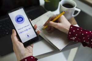 Junger Geschäftsmann nutzt KI-Chatbot in Computer- oder Mobilanwendung. Chatbot-Konversation, KI-Technologie (künstliche Intelligenz). Futuristische Technologie. Virtueller Assistent im Internet. Einsatz von KI im Büro.