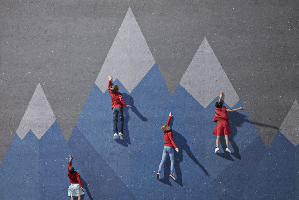 Vier Schülerinnen und Schüler liegen auf Asphalt mit gemalten Bergen, als ob sie klettern. Symbolisch für Klassenfahrt, Aufsichtspflicht und Risiko bei Bergwanderung.