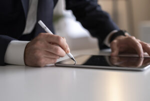 Person schreibt mit einem digitalen Stift auf ein Tablet im Büro