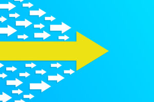 Gelber Pfeil führt viele kleine weiße Pfeile an – Symbol der Schulleitung, um Demokratische Schulkultur Kompetenz gestalten zu können.