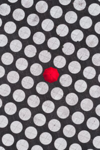 Luftaufnahme eines roten Regenschirms auf einem gepflasterten Platz mit regelmäßig angeordneten weißen Kreisen.