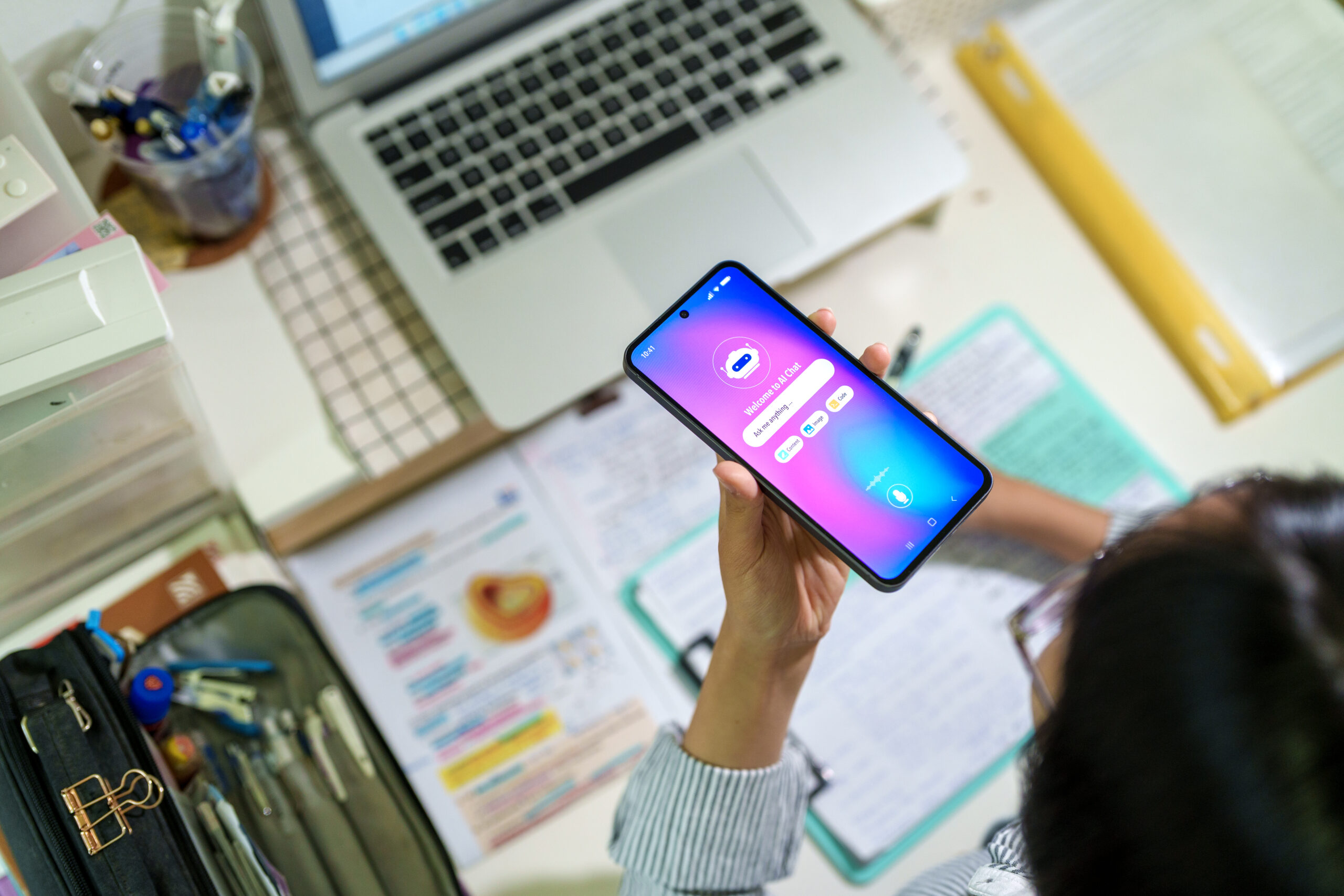 Eine Schülerin befragt via Handy einen KI-Chatbot, während sie ihre Hausaufgaben macht.