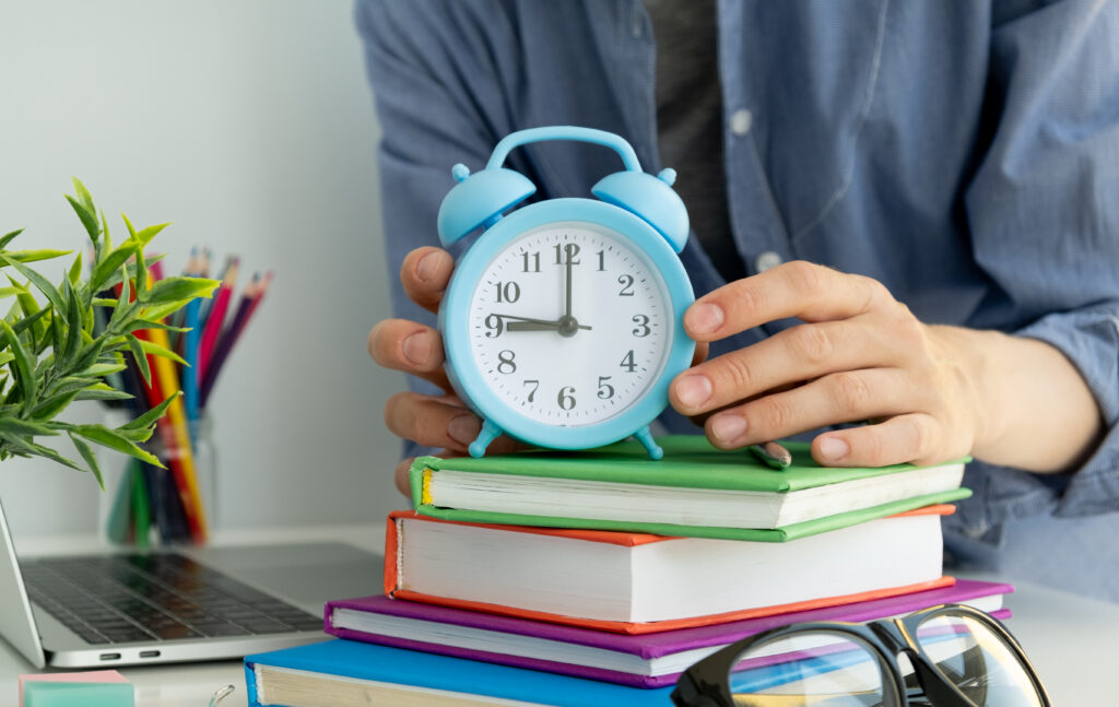 Ein Lehrer hält eine Uhr in der Hand.