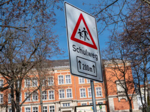 Das Bild zeigt ein Warnschild "Schulweg" am Straßenrand