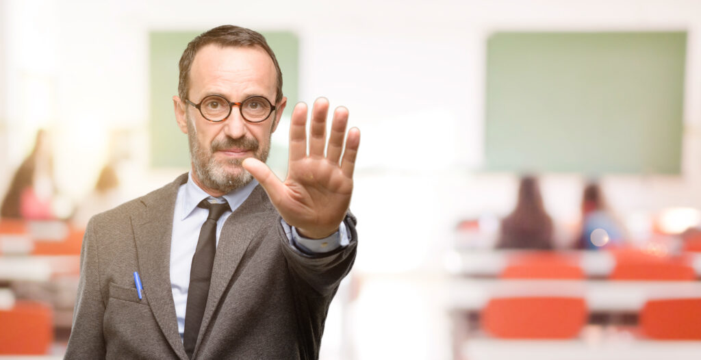 Ein Lehrer hebt energisch die Hand, um "Stop" zu sagen.