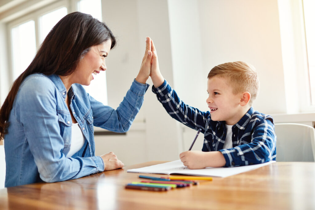 Eine Schulbegleiterin und ein Schüler geben sich "high five".